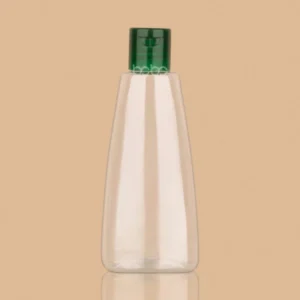 A clear 100ml transparent PET Nihar hair oil bottle with a green flip-top cap.