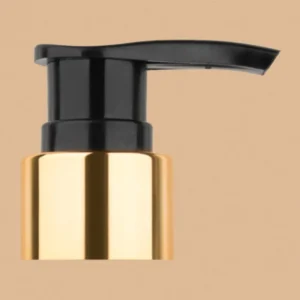 Black and gold lotion pump dispenser head against a tan background.